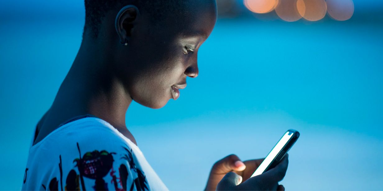 A young woman illuminated by her phone